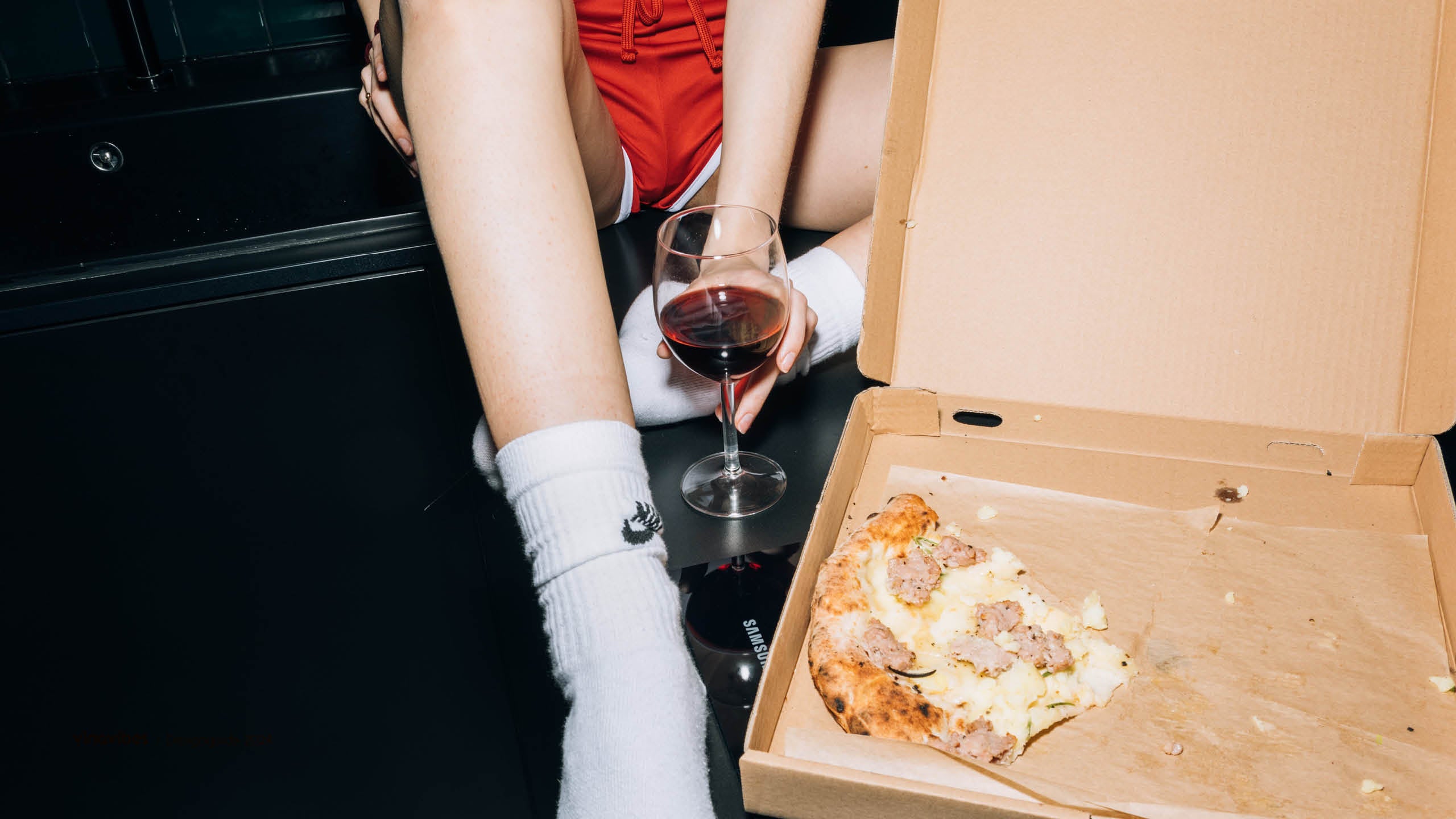 Pige, der nyder et glas vin og en pizza i afslappede omgivelser fra Vinovibes